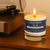 Hand-poured candle labeled 'Apartment 30-B' with its packaging on a gray background