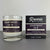 Hand-poured candle labeled 'Apartment 30-B' with its packaging on a gray background